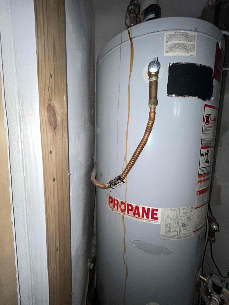 old water heater with dirty water leaking down the side