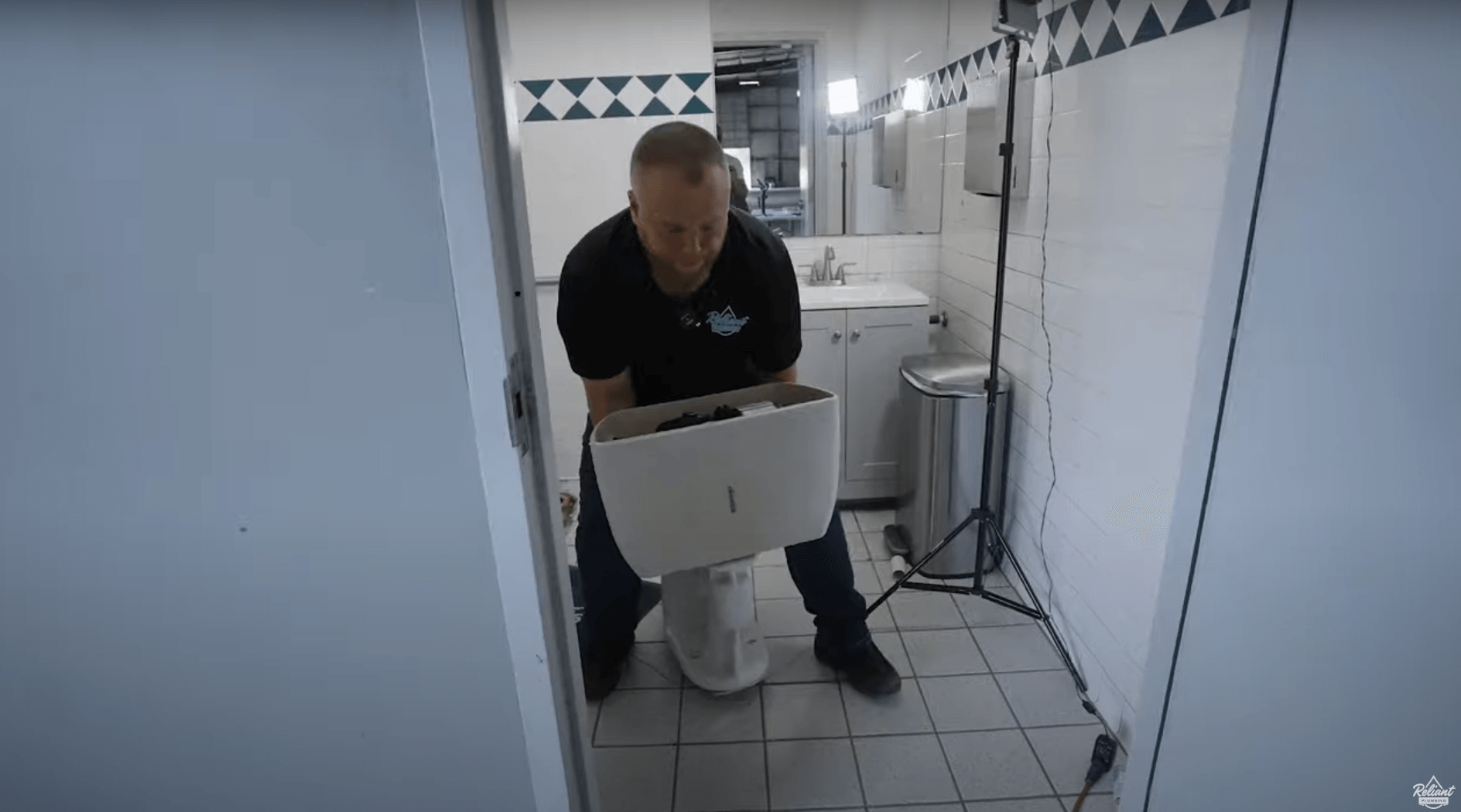 a plumber carrying an old toilet out of a bathroom