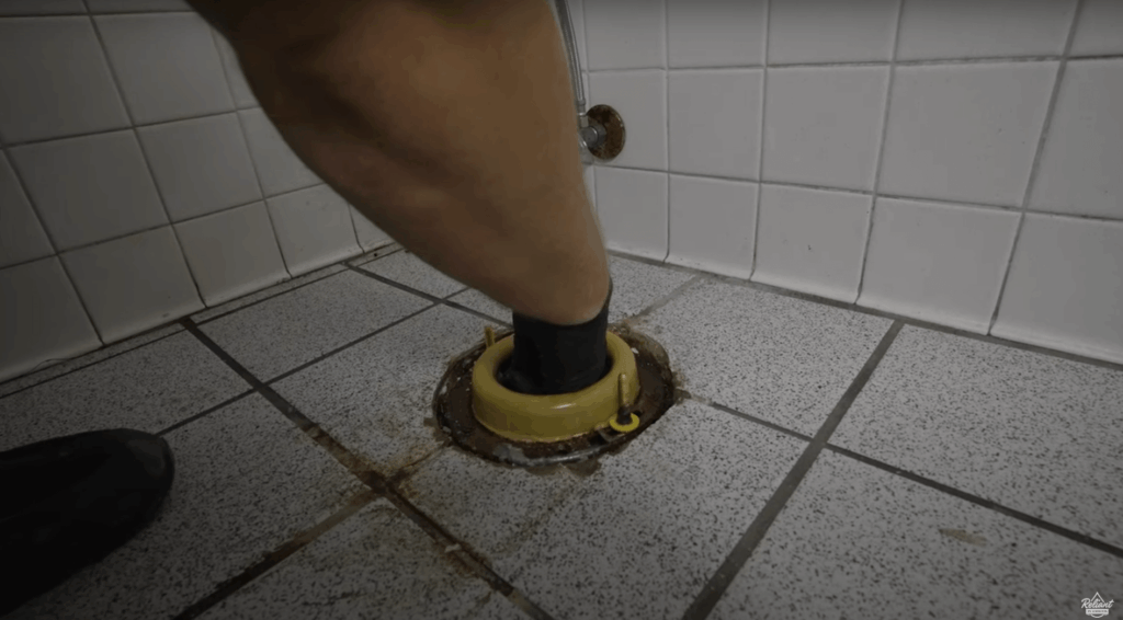 placing a thick wax ring into the drain on the floor where a new toilet will be installed