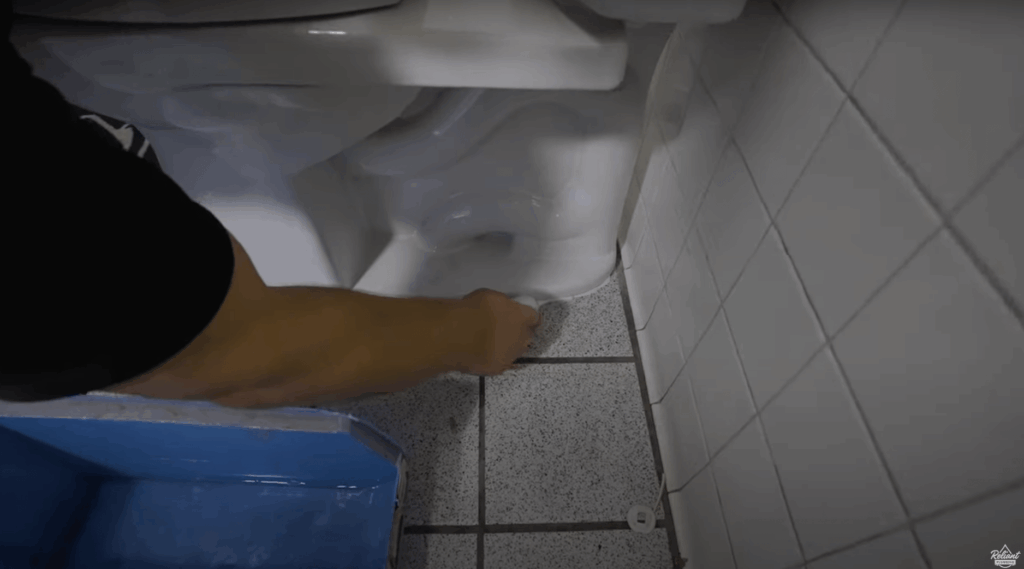 plumber applying sealant to the base of a newly installed toilet
