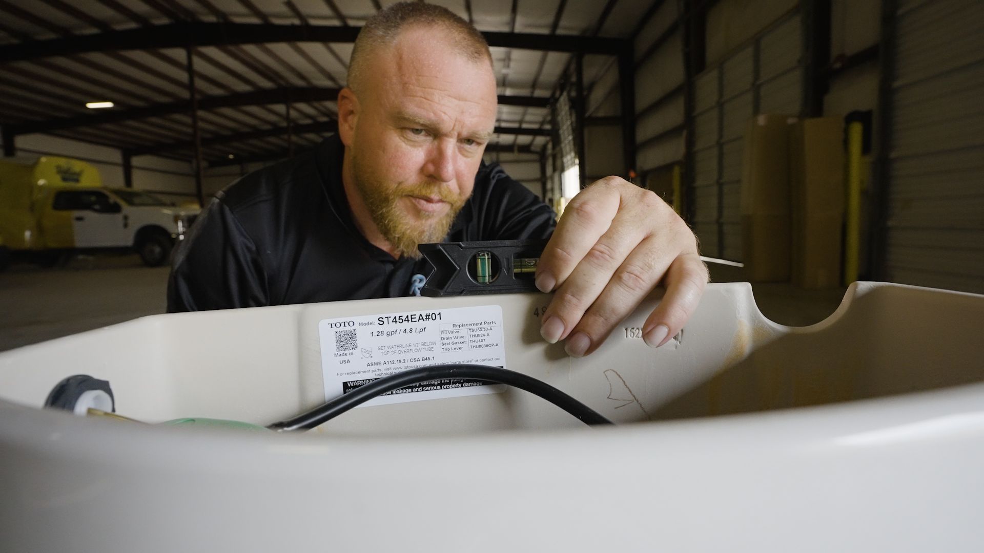 Max Hicks, owner of reliant plumbing holding a level on top of a toilet tank