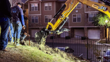 plumbers using excavator to dig up main water line at an apartment complex