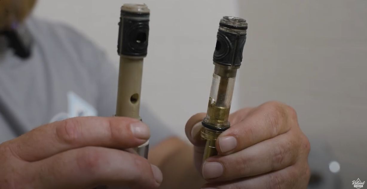 two shower valve cartridges held side by side with the old cartridge on the left and the new on the right