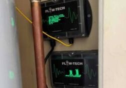 Two flowtech home descaling devices installed in closet next to water heater