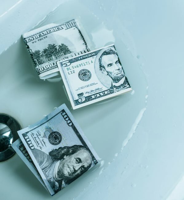 two hundred-dollar bills and a five dollar bill soaking in a sink of water